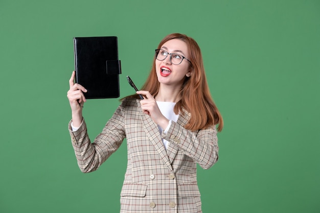 Portret van vrouwelijke leraar met notitieblok op groen