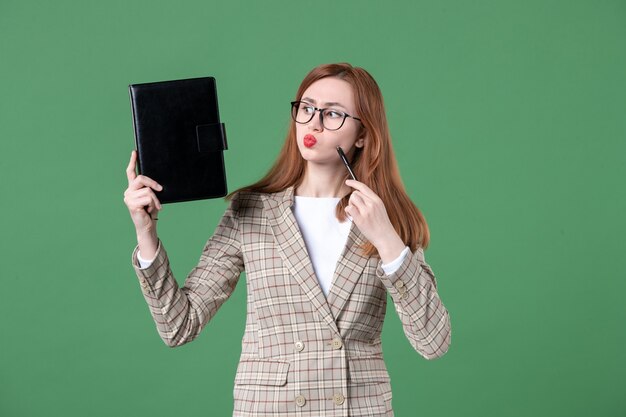 Portret van vrouwelijke leraar met notitieblok op groen