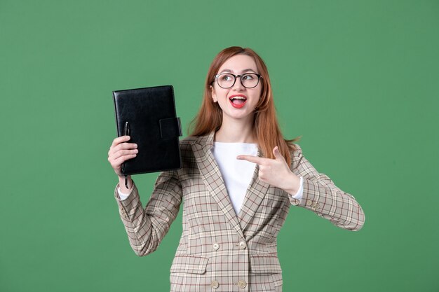 Portret van vrouwelijke leraar met notitieblok op groen