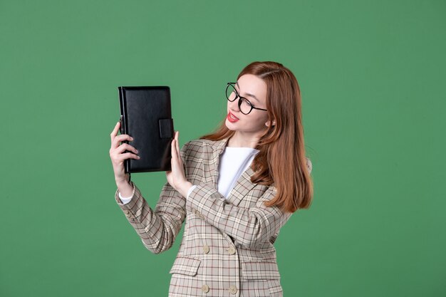 Portret van vrouwelijke leraar met notitieblok op groen