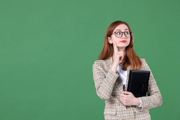 Portret van vrouwelijke leraar met notitieblok op groen