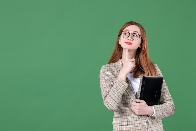 Portret van vrouwelijke leraar met notitieblok op groen