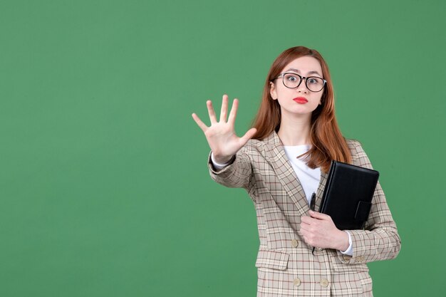 Portret van vrouwelijke leraar met notitieblok op groen