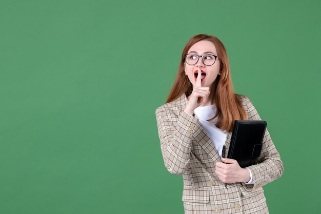 Portret van vrouwelijke leraar met notitieblok op groen