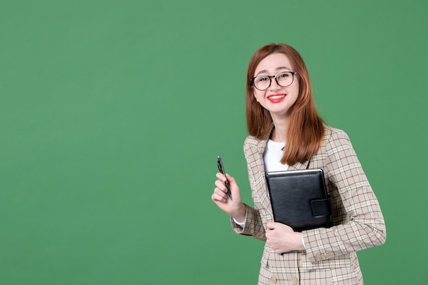 Portret van vrouwelijke leraar met notitieblok op groen