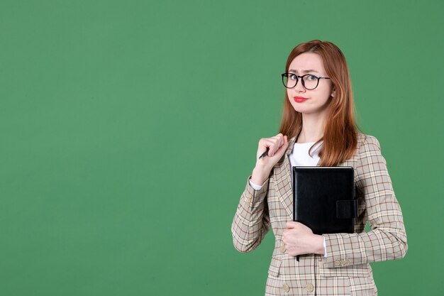 Portret van vrouwelijke leraar met notitieblok op groen