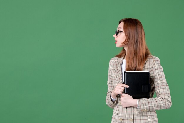Portret van vrouwelijke leraar met notitieblok op groen