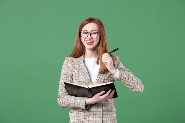 Portret van vrouwelijke leraar met notitieblok op groen