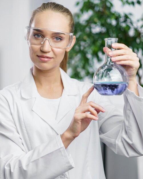 Portret van vrouwelijke onderzoeker in het laboratorium met reageerbuis en veiligheidsbril