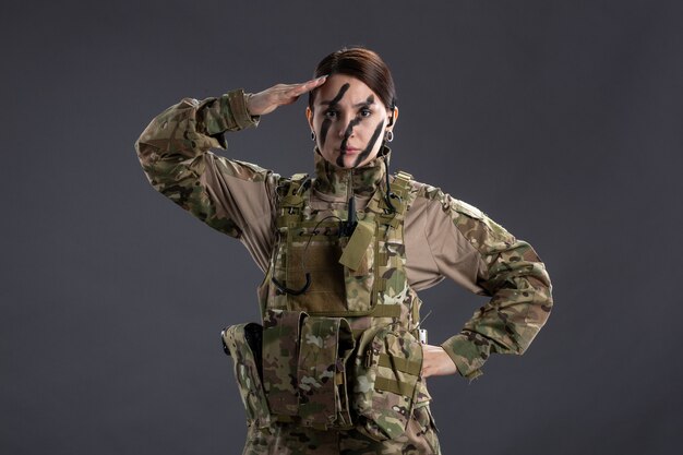 Portret van vrouwelijke soldaat in camouflage op de donkere muur