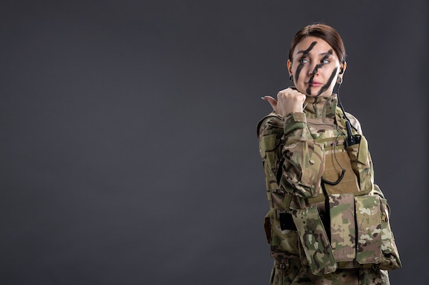 Gratis foto portret van vrouwelijke soldaat in camouflage op de donkere muur