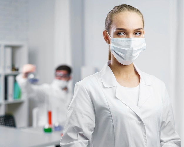 Portret van vrouwelijke wetenschapper in het laboratorium met medisch masker