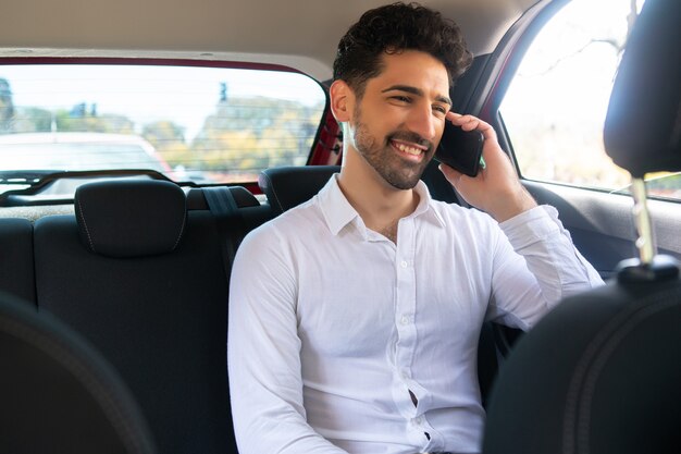 Portret van zakenman die aan de telefoon praat op weg naar zijn werk in een auto