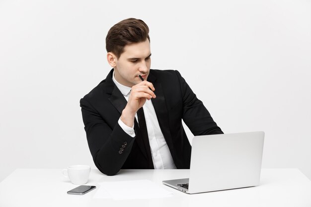 Portret van zelfverzekerde manager zit aan de balie. Portret van zakenman aan het werk op de computer. Succesvolle formele man in zijn nieuwe moderne kantoor.