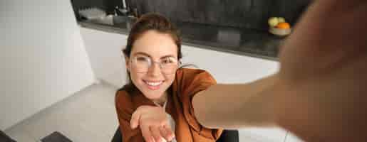 Gratis foto portret van zorgeloze jonge vrouw in een bril die een selfie maakt van thuis lifestyle blogger die foto's maakt