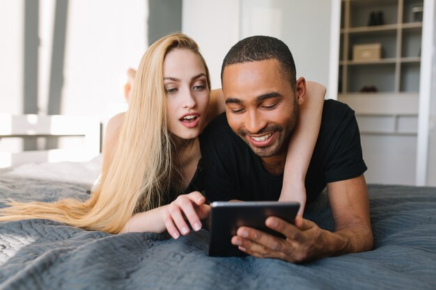 Portret vreugdevolle paar koelen op bed, plezier met tablet. Goedemorgen samen, zoeken op internet, relaties, echte positieve emoties uiten, opgewekte stemming