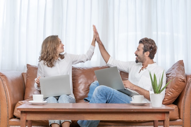 Portret zakenman en zakenvrouw geven hi5 met behulp van de computer laptop thuis kantoor