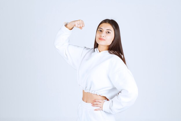 positief jong meisjesmodel dat haar biceps toont.