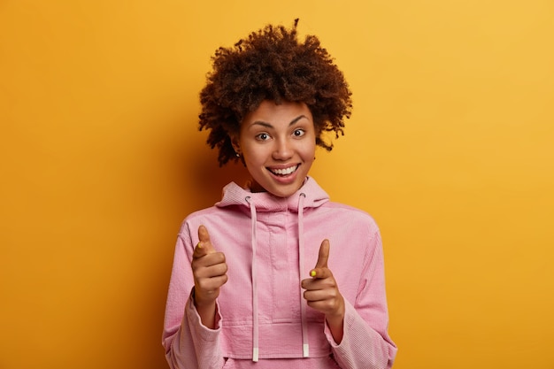 Positieve donkere jonge vrouw wijst naar je, drukt keuze uit