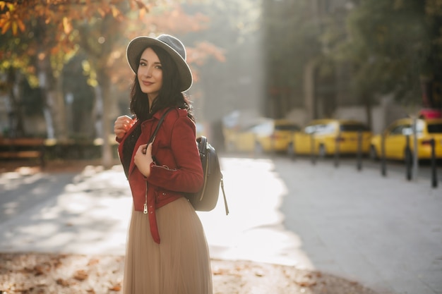 Positieve donkerharige vrouw in hoed ontspannen in herfst park