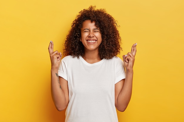 Positieve gekrulde vrouw kruist vingers