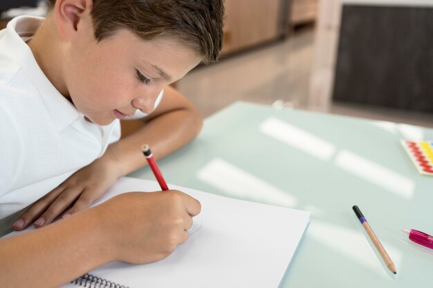 Positieve jonge jongen die zijn huiswerk doet