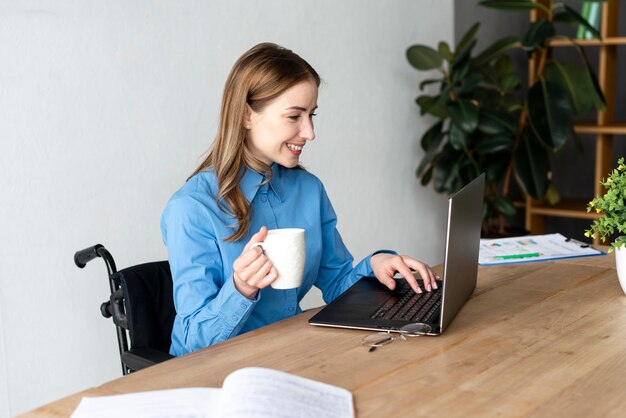 Positieve jonge vrouw die van koffie geniet op het kantoor