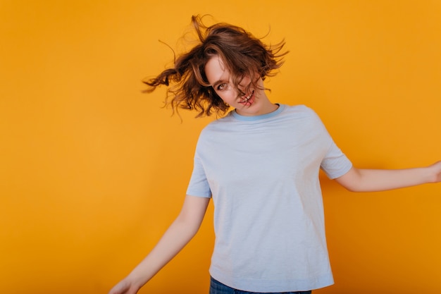 Positieve jonge vrouw met trendy kapsel dansen in blauw t-shirt