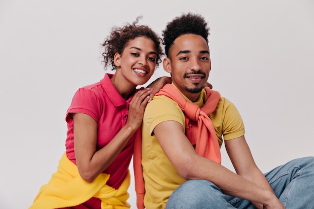 Positieve man en vrouw die met een glimlach in de camera kijken op geïsoleerde muur