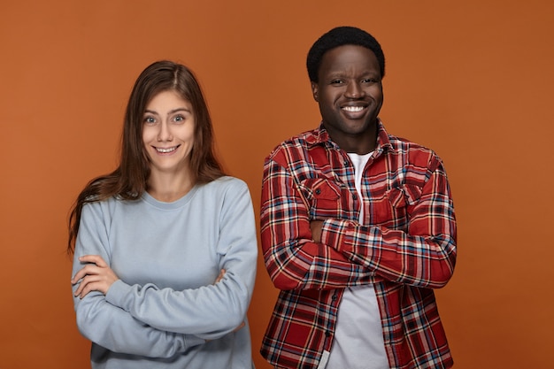 Positieve menselijke emoties, gevoelens, reactie en houding. Grappige schattige witte vrouw met losse haren poseren met haar zwarte man, met clueless, verwarde of verbaasde gezichtsuitdrukkingen, glimlachend