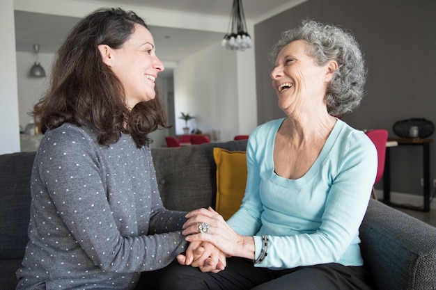 Positieve oudere vrouw en haar dochter chatten, lachen