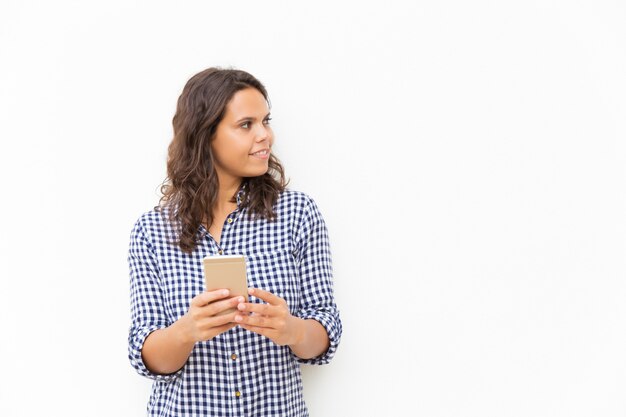 Positieve peinzende Latijnse vrouw met cellphone