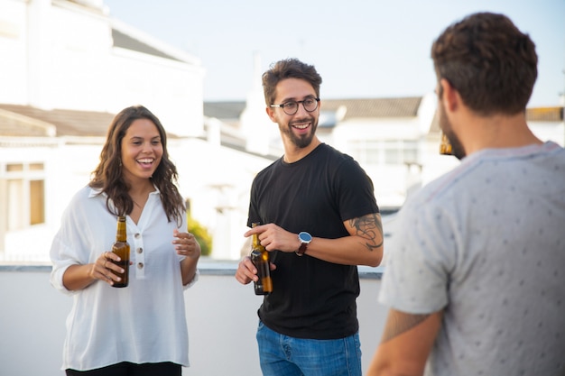 Positieve vrolijke vrienden praten, lachen en bier drinken
