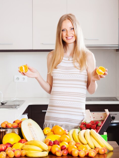 Positieve vrouw met sinaasappelen en andere vruchten