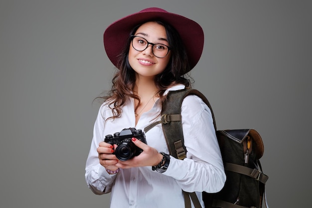 Positieve vrouwelijke toerist met fotocamera en reisrugzak.