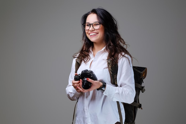 Positieve vrouwelijke toerist met fotocamera en reisrugzak.