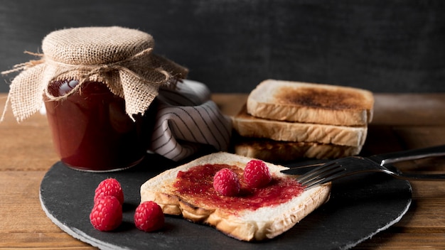 Pot met frambozenjam met brood en mes