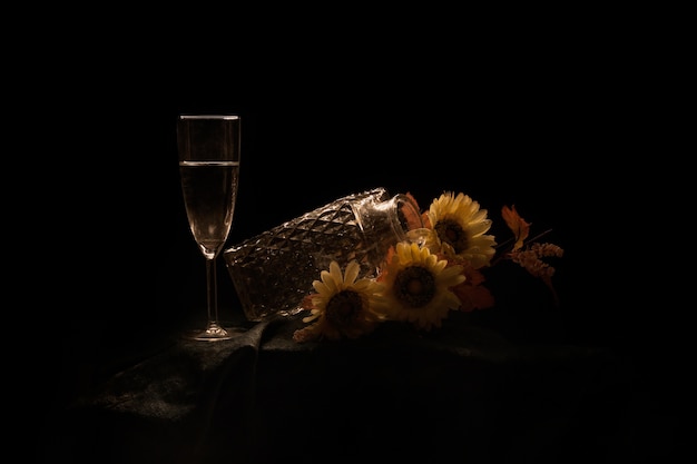 Pot met zonnebloemen en een glas champagne op tafel geïsoleerd op een zwarte achtergrond