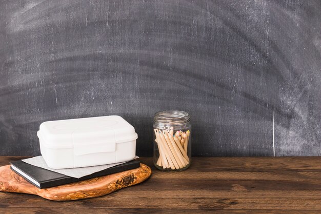 Potloden dichtbij plastic lunchbox en notitieboekje