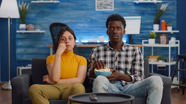 Pov van interraciaal koppel dat film op tv kijkt met een snack