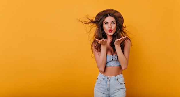 Prachtig gelooid meisje met rode lippenstift met plezier op gele ruimte