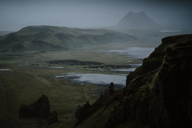 Gratis foto prachtig groen landschap met een meer omgeven door hoge bergen gehuld in mist