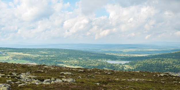 Prachtig groen landschap omgeven door bergen onder een bewolkte hemel