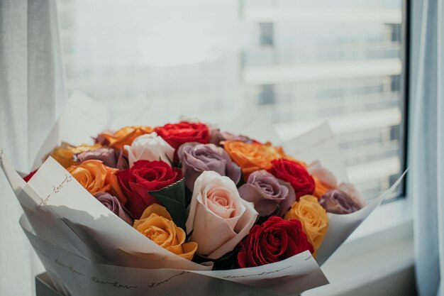 Prachtig kleurrijk natuurlijk rozen arrangement boeket met inpakpapier voor het raam