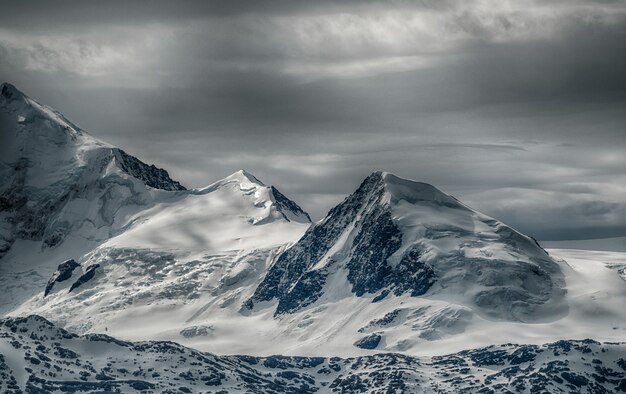 Prachtig landschap van een bergketen bedekt met sneeuw onder de bewolkte hemel