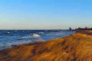 Gratis foto prachtig landschap van een met gras begroeide heuvel aan zee onder de adembenemende lucht