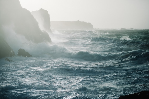 Gratis foto prachtig landschap van zeegolven die breken over rotsformaties