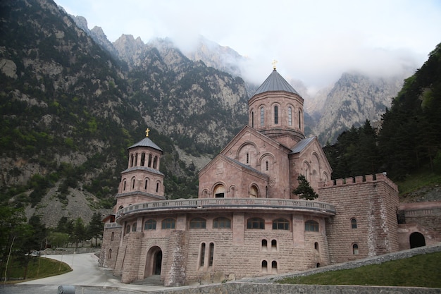 Gratis foto prachtig shot van een christelijke kerk met de bomen en bergen in georgië