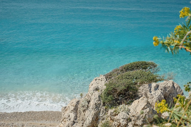 Prachtig stenen strand op een verlaten plek met turquoise zeerotsen en blauwe lucht op een zonnige dag Tropische zomervakantie aan het panoramisch uitzicht op de Egeïsche Zee