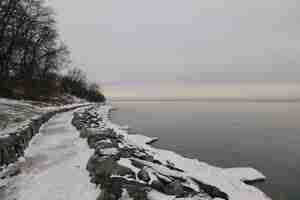 Gratis foto prachtig uitzicht op de sneeuw en bomen aan de kust bij het rustige meer